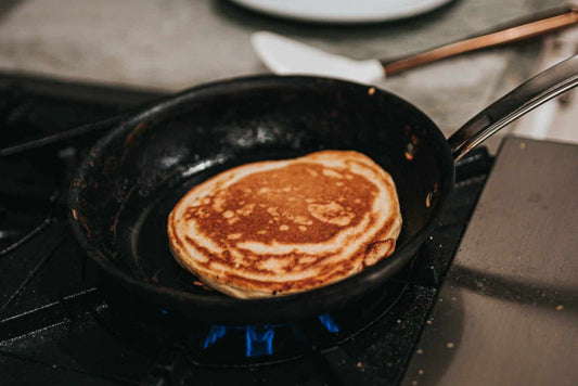 low carb pancakes being fried in a black pan.