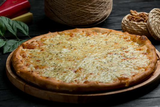 Low-Carb Chicken Alfredo Pizza on a wooden plate with herbs surrounding it