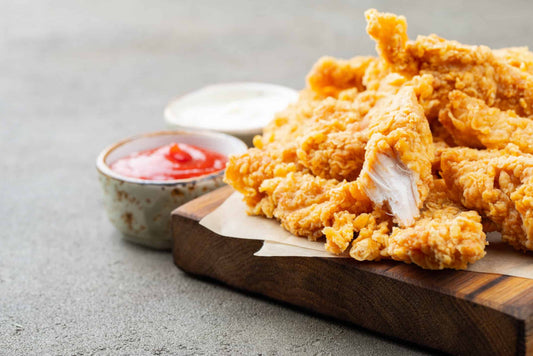 low-carb chicken nuggets on a wooden chopping board with ketchup and mayonnaise in the background.