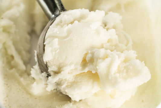 close up image of an ice cream scoop scooping vanilla ice cream
