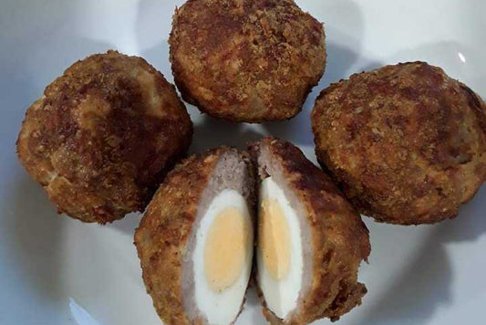 four low-carb scotch eggs on a plate, one of them is cut in half. 