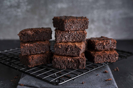 9 low-carb brownies in three stacks on a black kitchen counter, dark background