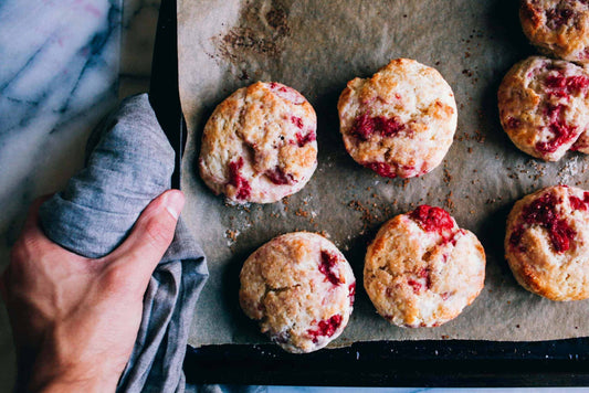six low carb sweet raspberry scones on a baking tray being taken out of the oven