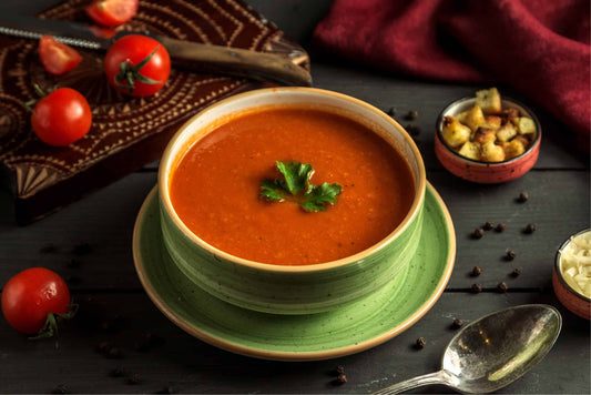 a green bowl of tomato soup with a parsley leaf on top