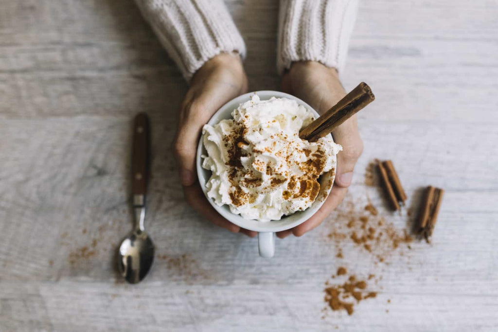 Low-carb hot chocolate in a mug topped with whipped cream and a dusting of cinnamon.