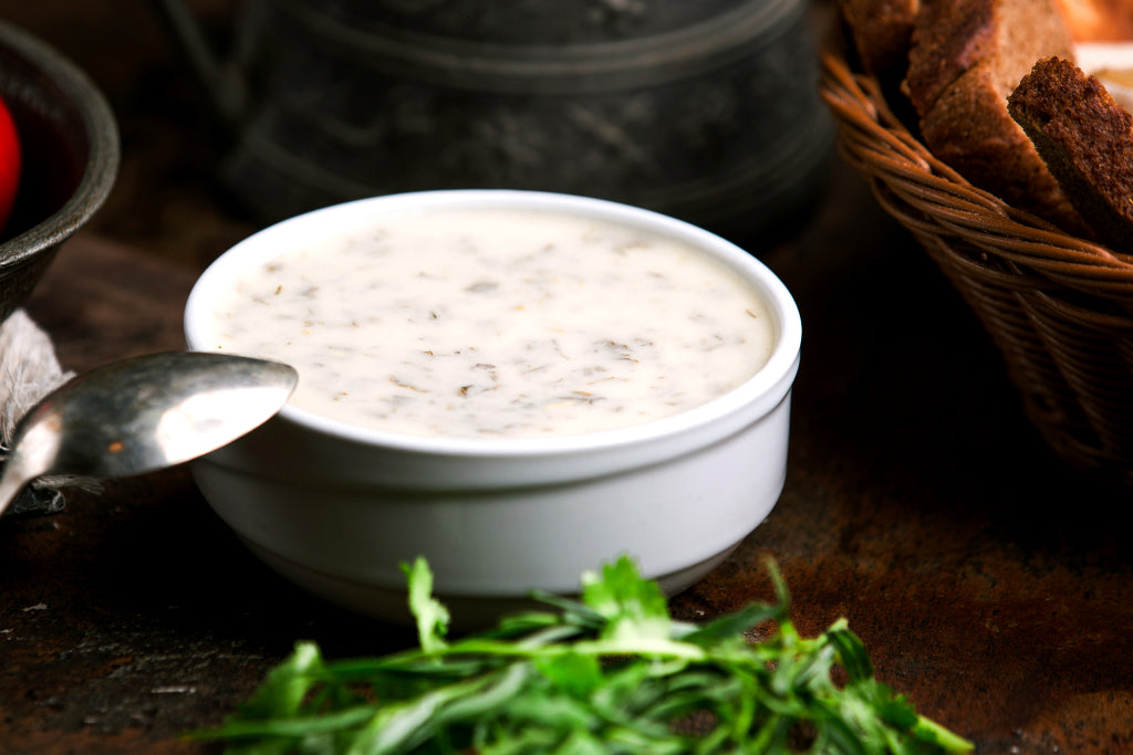 a close up photo of a white bowl with home made low-carb ranch dressing. A silver spoon is resting on the edge of the bowl