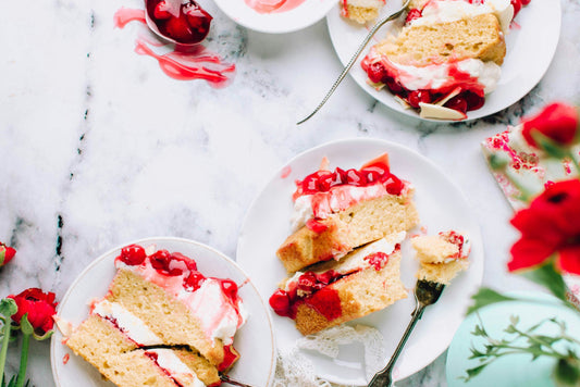 2 layers of low-carb victoria sponge on a cake stand. A white kitchen counter with a grey marble background