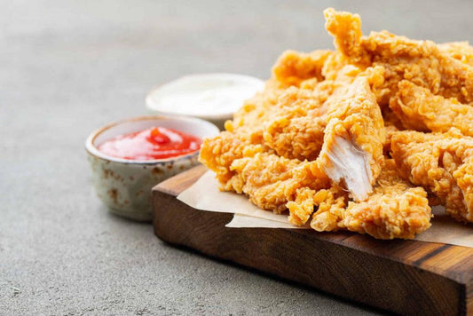 low-carb chicken nuggets on a wooden chopping board with ketchup and mayonnaise in the background.