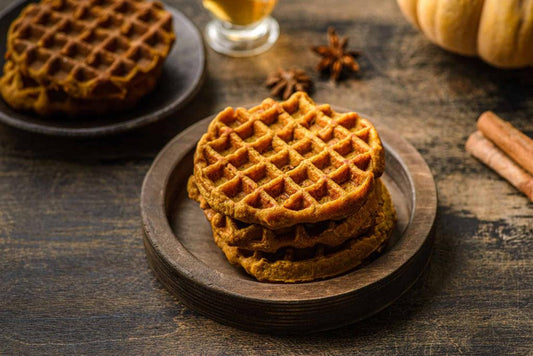 A stack of three low-carb pumpkin waffles on a wooden plate 