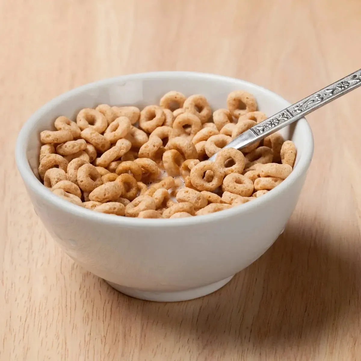 Crispy oat cereal rings with milk in a white bowl, ready to eat.