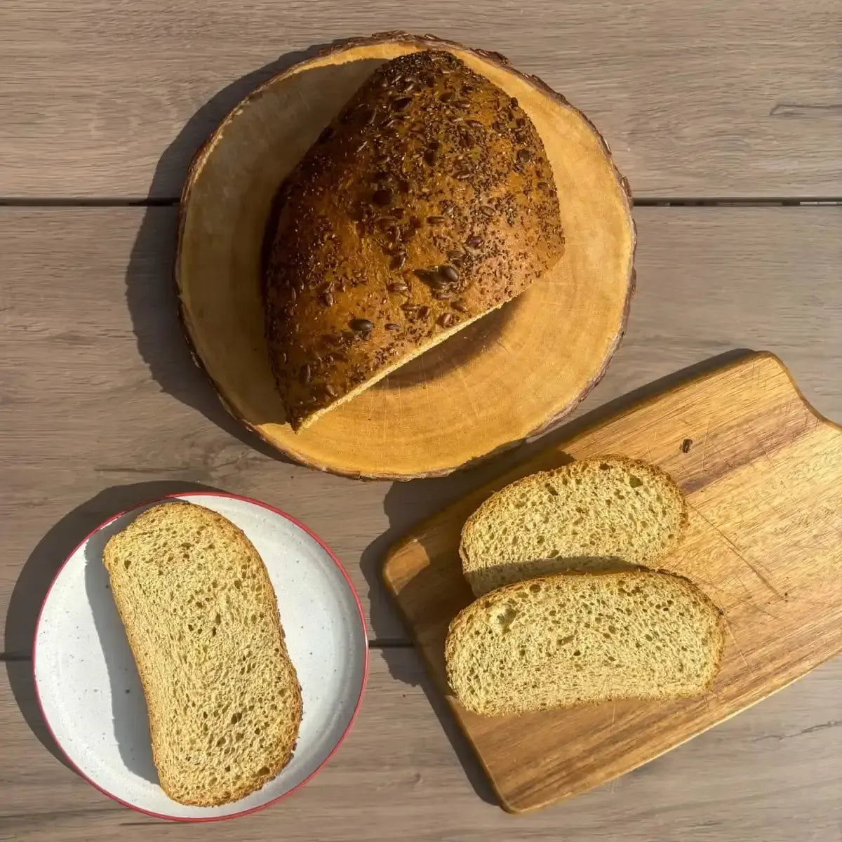 Rustic seeded bread loaf on a wooden board with sliced pieces, evoking fresh, wholesome baking.