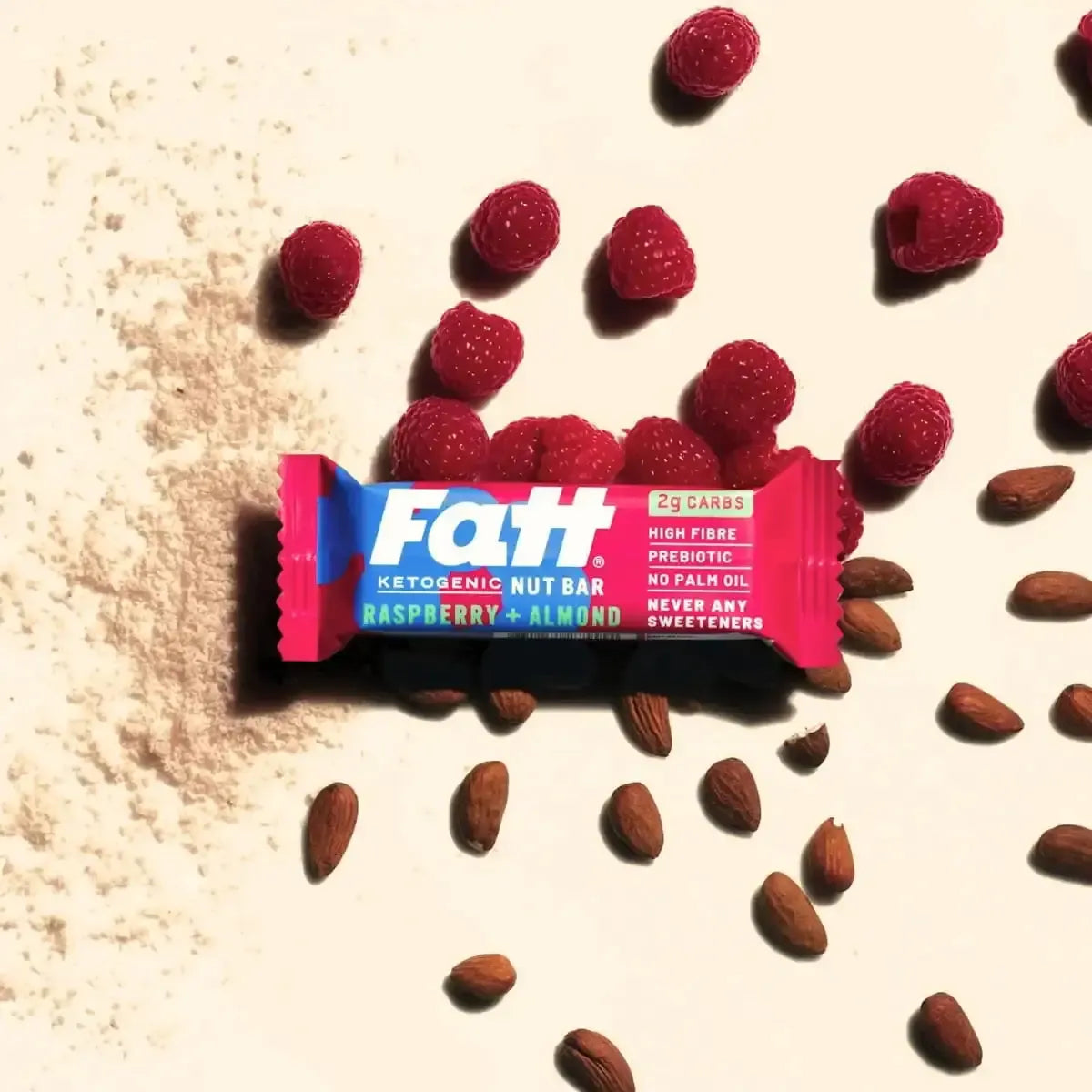 Fatt Snacks raspberry + almond ketogenic nut bar, fresh raspberries, and almonds on a light surface.