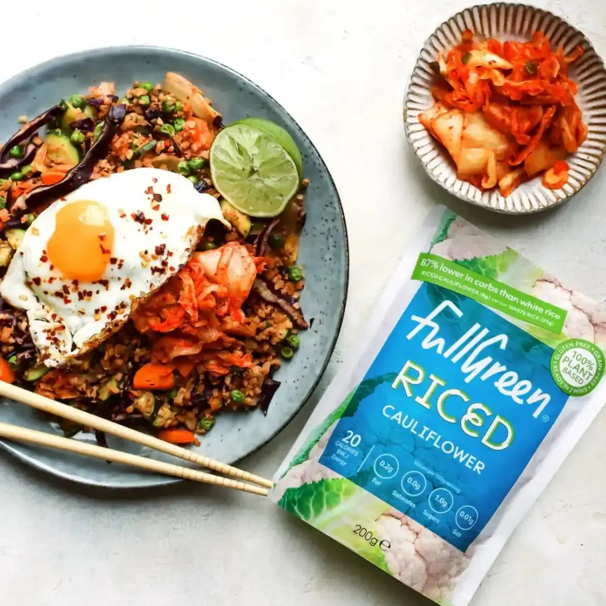 Fullgreen Riced Cauliflower meal with fried egg, kimchi, and lime, next to product packaging.