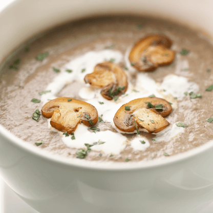 Creamy keto mushroom soup in a white bowl, garnished with sautéed mushroom slices, cream, and fresh parsley.