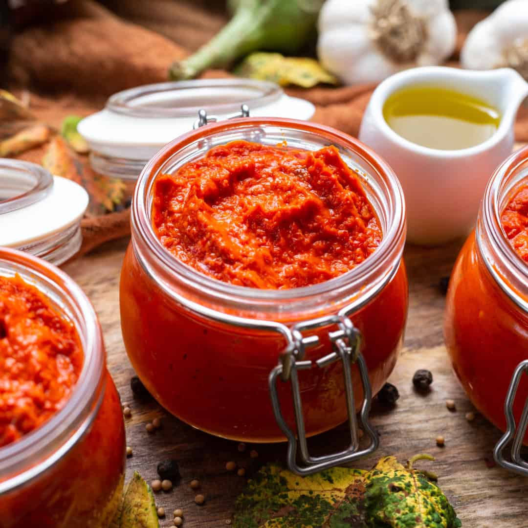 a close up image of a glass jar containing a red cooking sauce