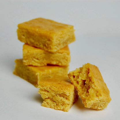 Stack of golden ketogenic vanilla praline blondies, one broken to show its soft texture.
