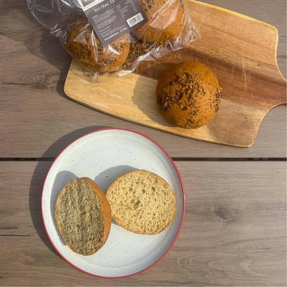 Packaged and sliced keto seeded bread rolls on a wooden board and white plate.