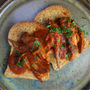 Two slices of toasted keto bread topped with rich red sauce and shredded meat, garnished with parsley.
