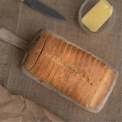 Sliced keto-friendly plain bread loaf on a wooden board with butter and a knife.