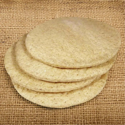 Stack of four round, light brown keto pizza bases on a rustic burlap background.