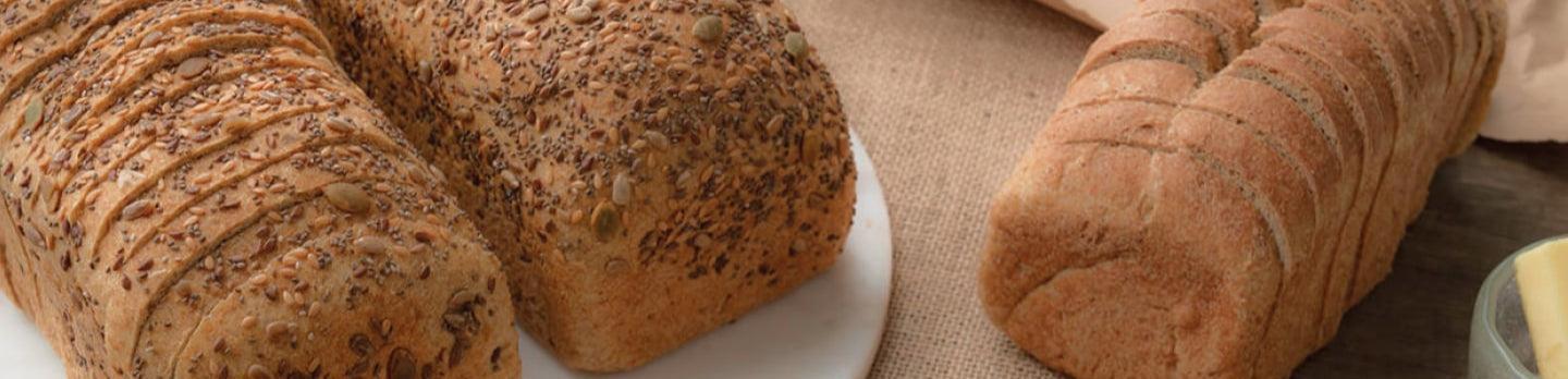 Assorted loaves of bread on a textured surface with a white plate.